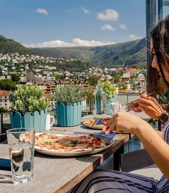 gjest spiser pizza på takterrasse